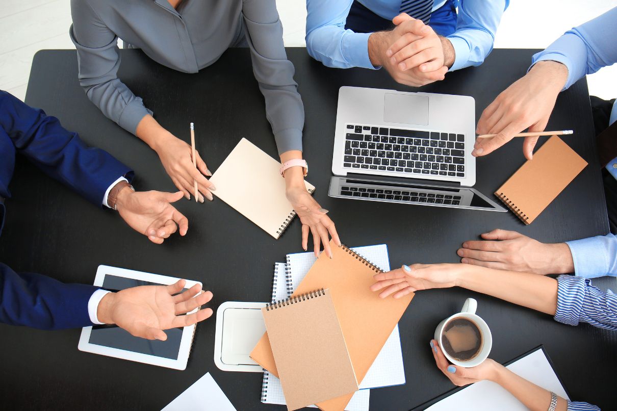 Business professionals collaborating at a table, engrossed in work with laptops and papers.