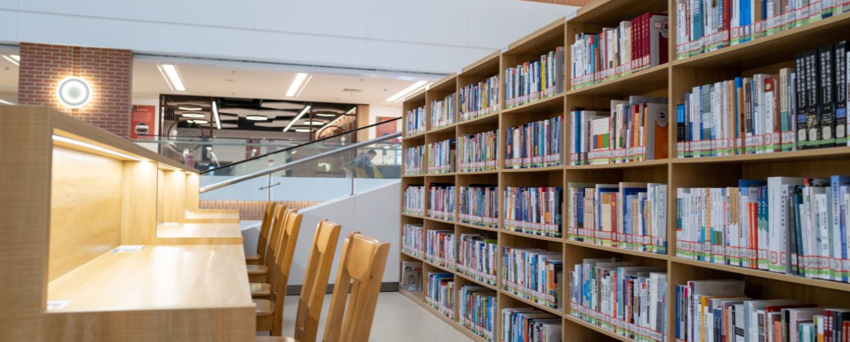 A cozy library featuring wooden benches and tall bookshelves filled with books, inviting readers to explore.