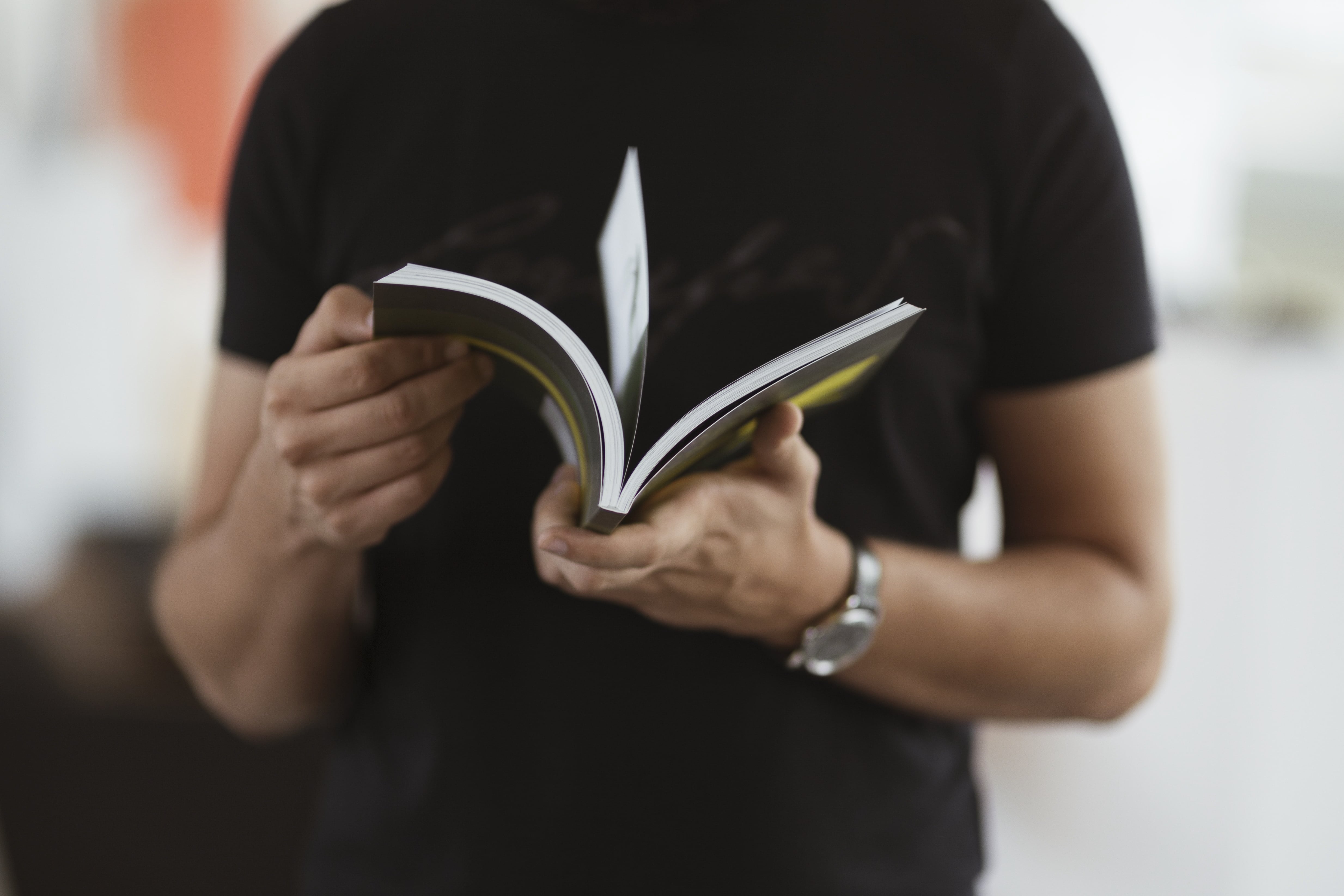 A man holding an open book, engrossed in reading.